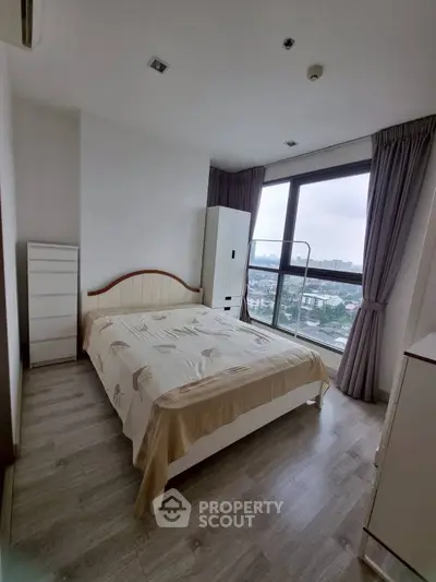 Cozy bedroom with large window offering stunning city view, modern furniture, and elegant decor.