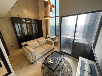 Modern living room with high ceiling and city view, featuring elegant furniture and large windows.