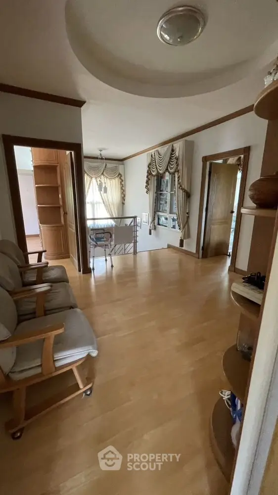 Charming hallway with wooden flooring and elegant drapery leading to a cozy living area.