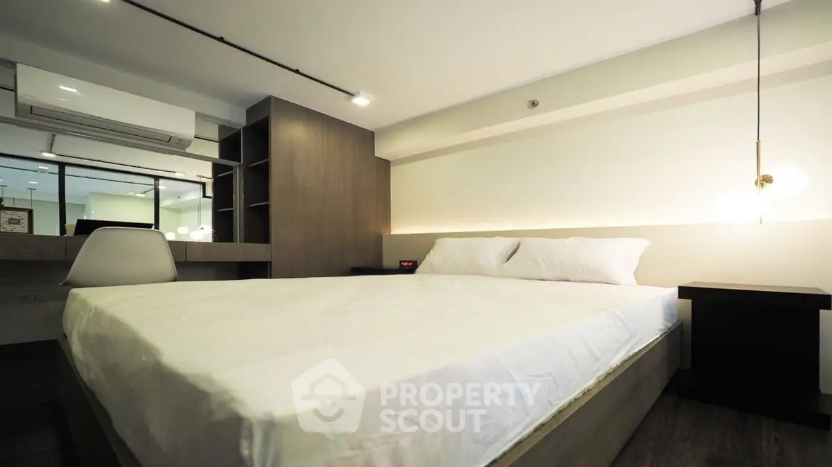 Modern bedroom with stylish decor and ambient lighting, featuring a comfortable bed and workspace.