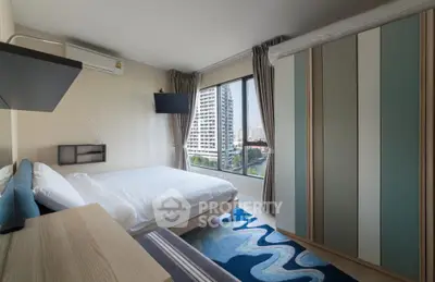 Modern bedroom with large window and stylish decor in urban apartment.