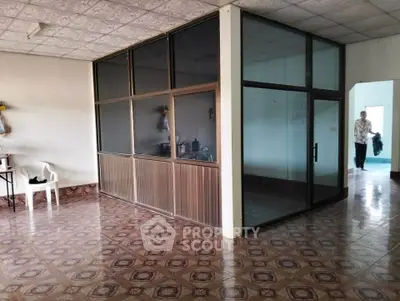 Spacious interior with unique tile flooring and glass partition, ideal for versatile living or office space.