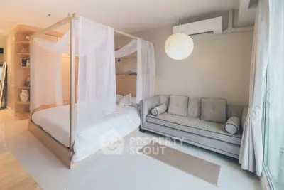 Elegant bedroom with canopy bed and cozy sofa in modern apartment