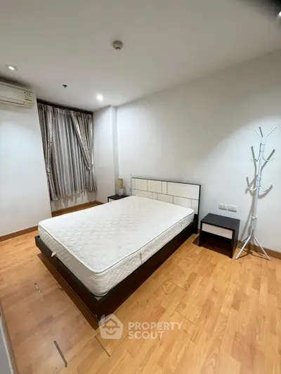 Spacious bedroom with modern design and wooden flooring, featuring a comfortable bed and stylish decor.