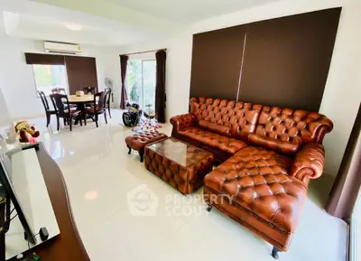 Spacious living room with elegant leather furniture and dining area, featuring large windows and natural light.