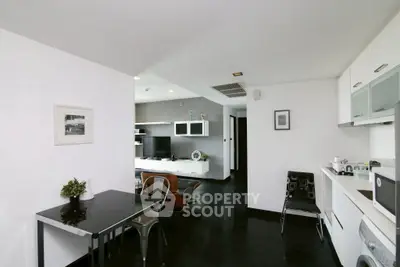 Modern open-plan living room and kitchen with sleek black flooring and minimalist decor.