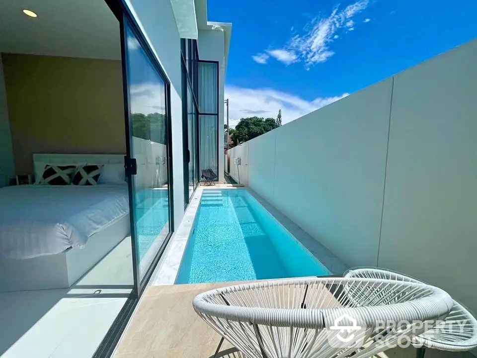 Luxurious private pool next to modern bedroom with glass sliding doors and stylish outdoor seating.