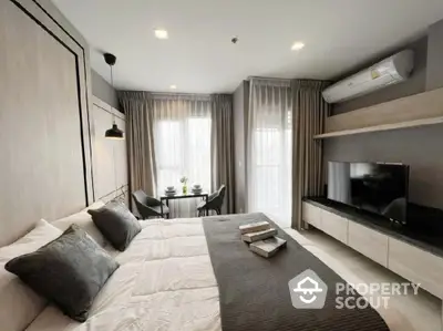 Modern bedroom with stylish decor and natural light, featuring a cozy bed and a wall-mounted TV.