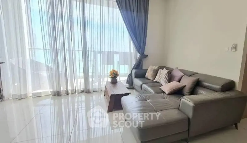 Spacious living room with modern sofa and stunning ocean view through large windows.