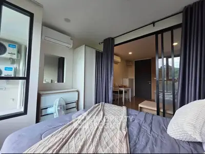 Modern bedroom with sliding glass doors leading to dining area, featuring air conditioning and stylish decor.