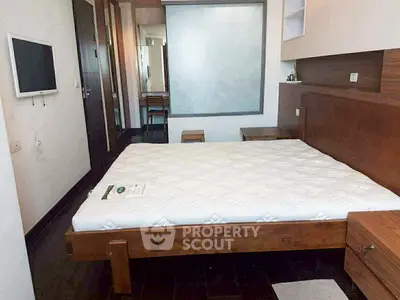 Spacious bedroom with modern wooden furniture and wall-mounted TV