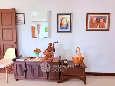 Charming living room with elegant decor and artistic wall paintings, featuring a wooden cabinet and stylish seating.