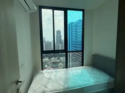 Modern bedroom with city view and large window in high-rise apartment