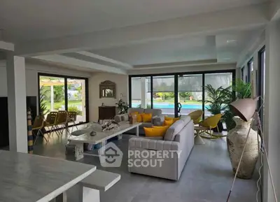 Spacious modern living room with pool view, large windows, and stylish decor, perfect for luxury living.