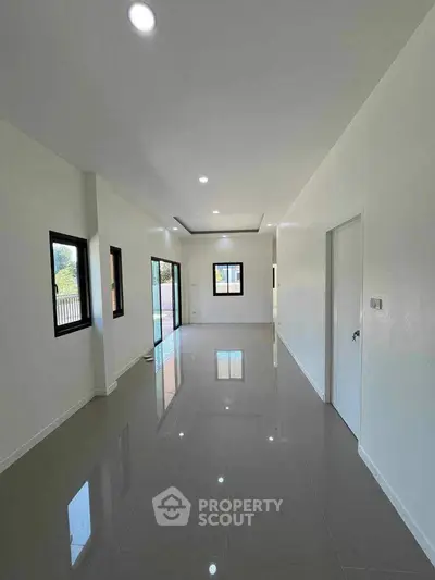 Spacious modern living room with glossy tiled floors and large windows.