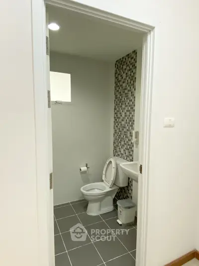 Modern bathroom with tiled walls and floor, featuring a toilet and sink.
