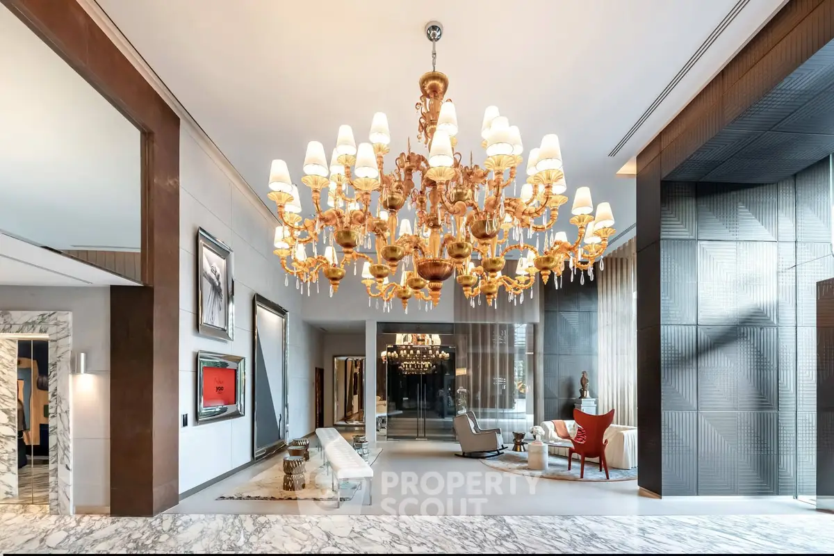 Luxurious lobby with grand chandelier and elegant seating area in upscale building.