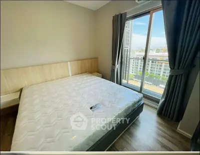 Modern bedroom with large window and city view, featuring a comfortable bed and stylish decor.