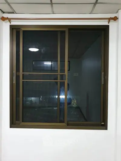 Modern sliding window with brown frame in a well-lit room, showcasing sleek design and functionality.
