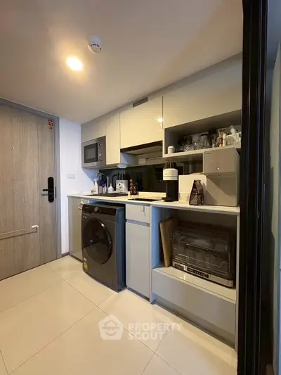 Modern compact kitchen with washing machine and microwave in sleek apartment