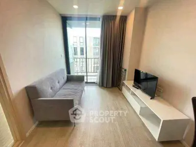 Modern living room with sleek sofa and TV, featuring a balcony view in a stylish apartment.