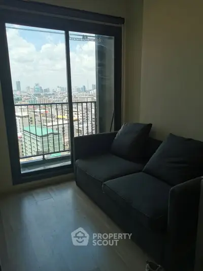 Cozy living room with city view from large window, featuring a comfortable sofa.