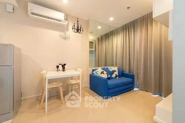 Modern living room with blue sofa, dining table, and mirrored wall for spacious feel.