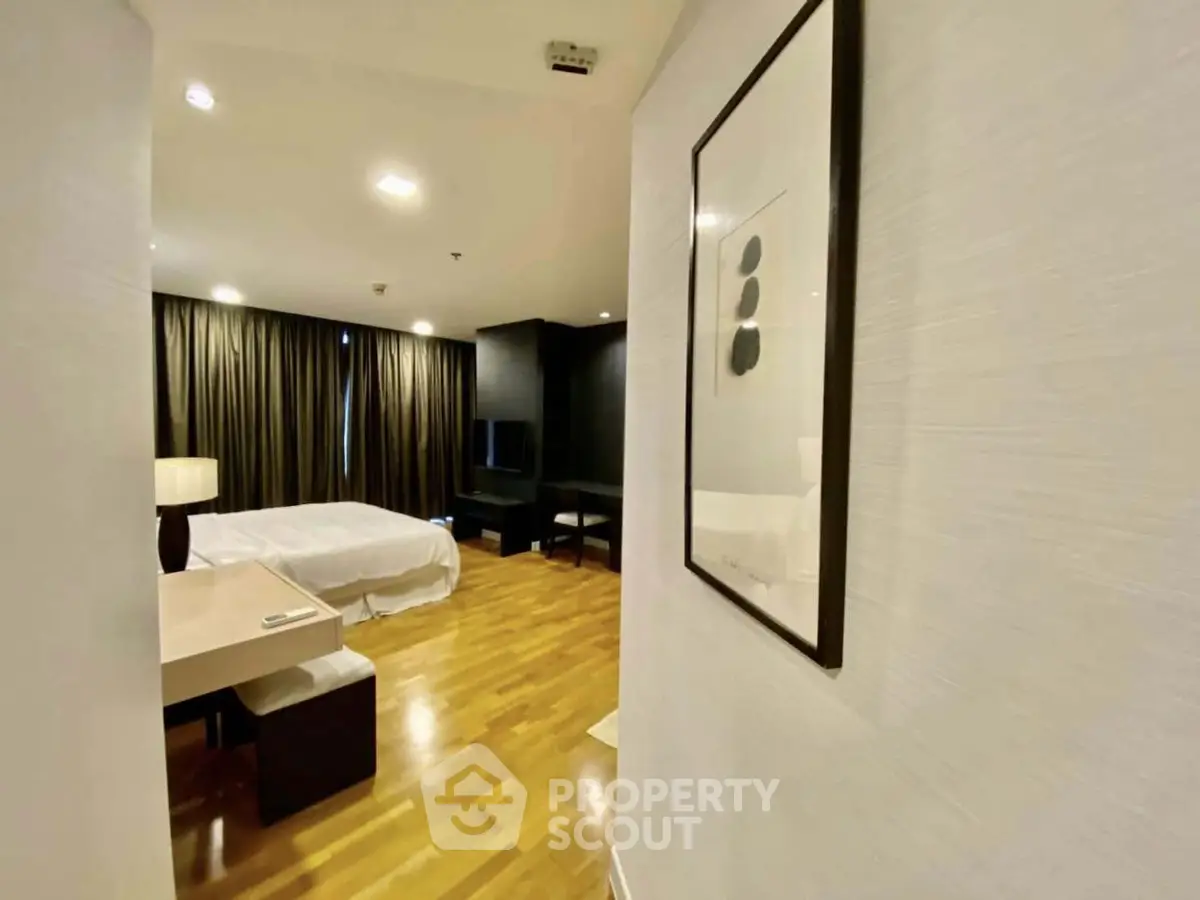 Spacious bedroom with modern decor and wooden flooring in luxury apartment.