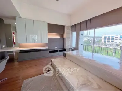 Spacious modern bedroom with large windows and scenic view, featuring sleek built-in storage and elegant wood flooring.