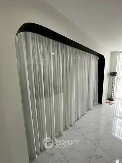 Elegant modern interior with floor-to-ceiling curtains and sleek marble flooring.