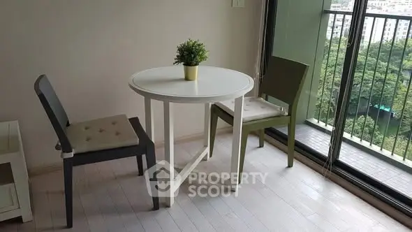 Charming apartment balcony with cozy seating and lush green view.