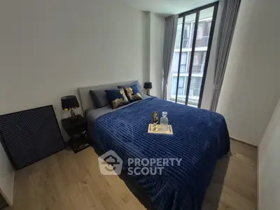 Modern bedroom with stylish decor and large window offering natural light.