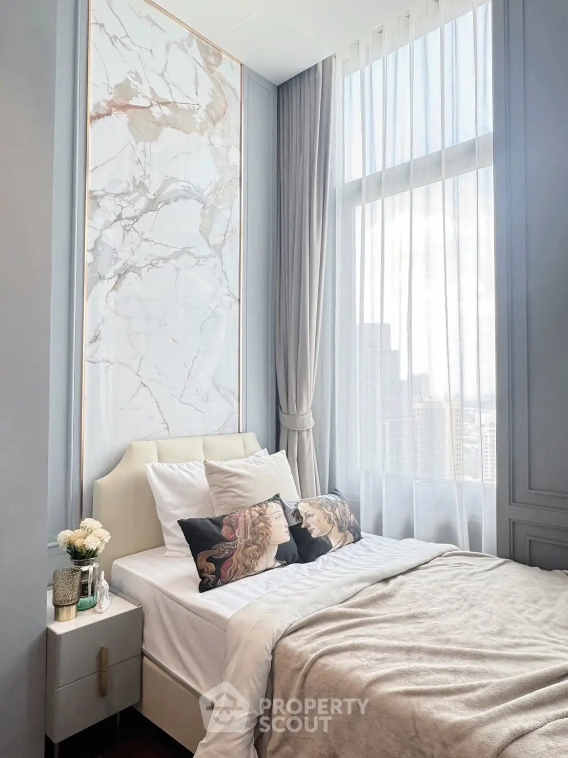 Luxurious bedroom with marble accent wall and large window offering city views.