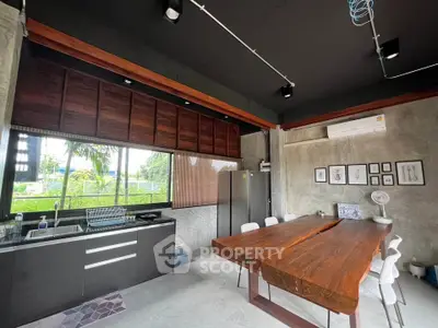 Modern kitchen with sleek design and wooden dining table, featuring open layout and natural light.