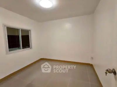 Spacious empty room with tiled floor and window, ideal for customization.