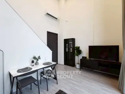 Modern living room with sleek furniture and high ceilings, featuring a minimalist dining area.