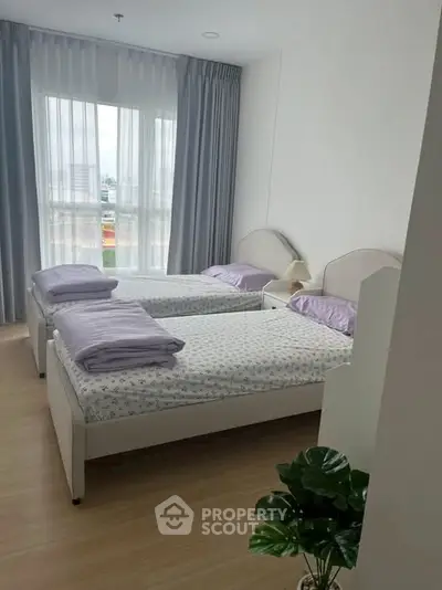 Bright and cozy bedroom with twin beds and large window in modern apartment.