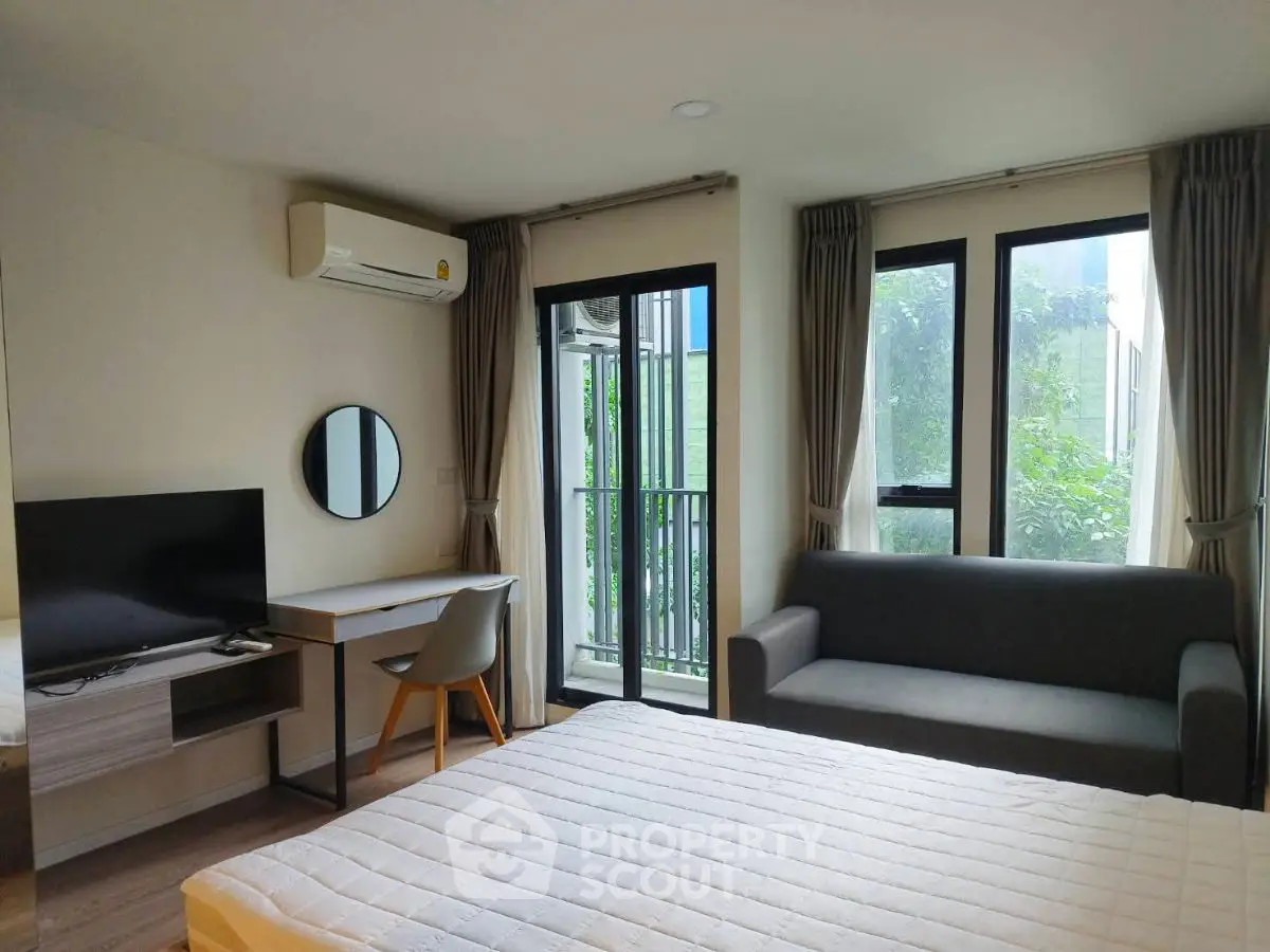 Modern bedroom with balcony, featuring a cozy sofa and study desk.