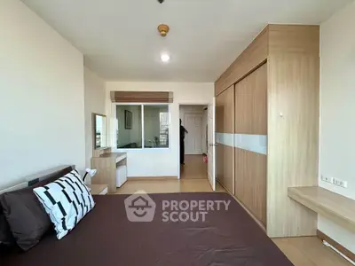 Spacious bedroom with modern wooden wardrobe and cozy bed in a well-lit apartment.