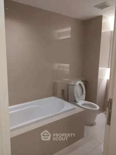 Modern bathroom with sleek bathtub and toilet in minimalist design.