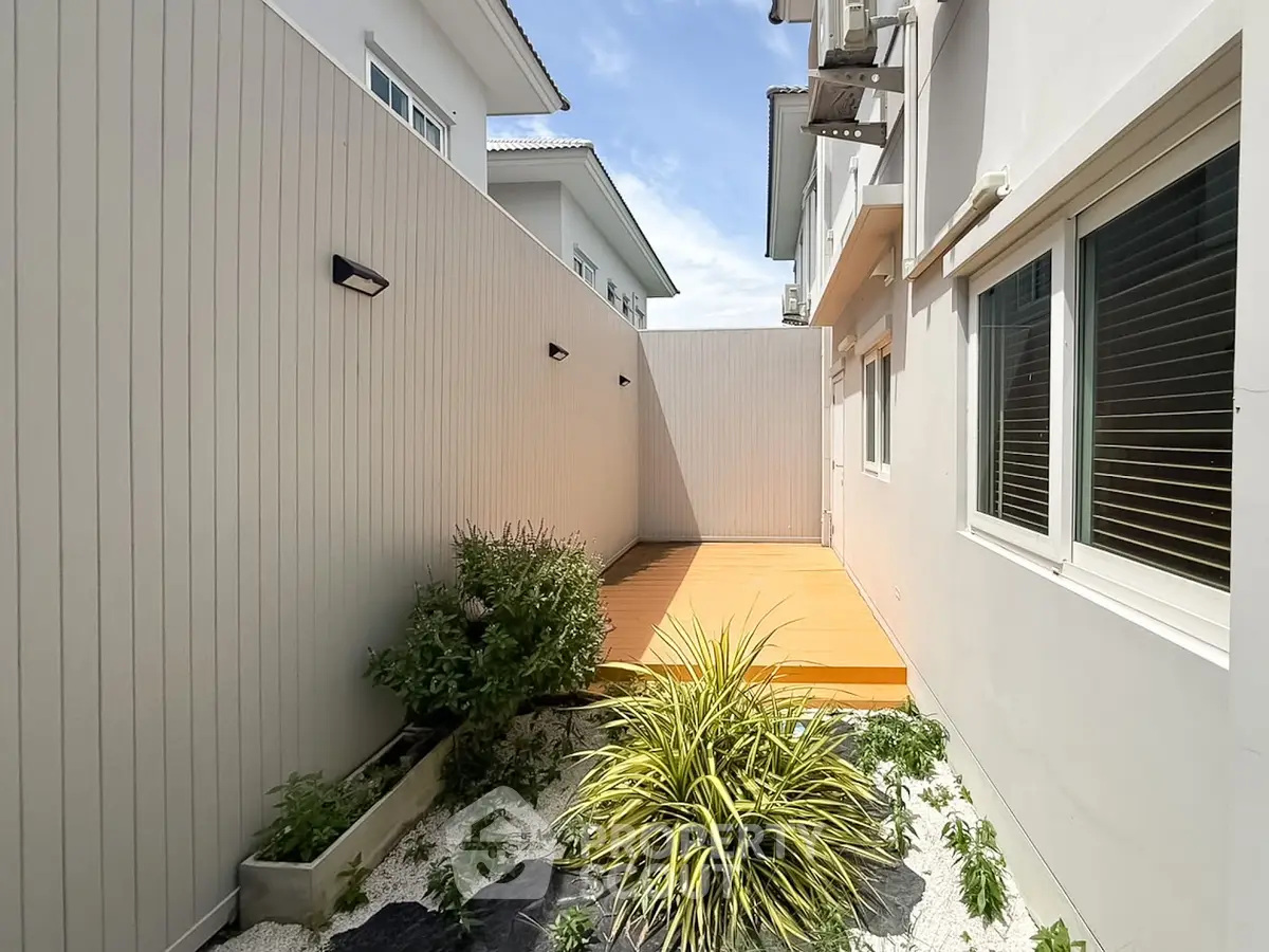 Charming townhouse exterior with private garden and wooden deck, perfect for relaxation and outdoor activities.