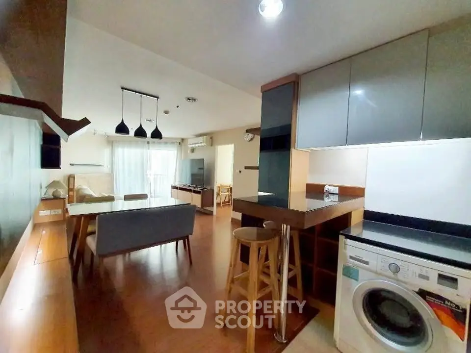 Modern open-plan kitchen and living area with washing machine and stylish decor.