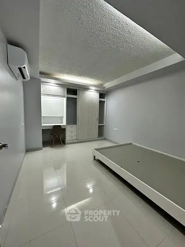 Spacious unfurnished bedroom with built-in wardrobe and modern lighting