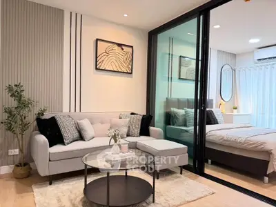 Modern living room with stylish decor and sliding glass doors leading to a cozy bedroom.