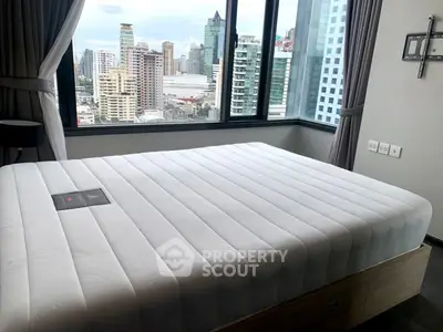 Spacious bedroom with city view and modern decor in high-rise apartment.