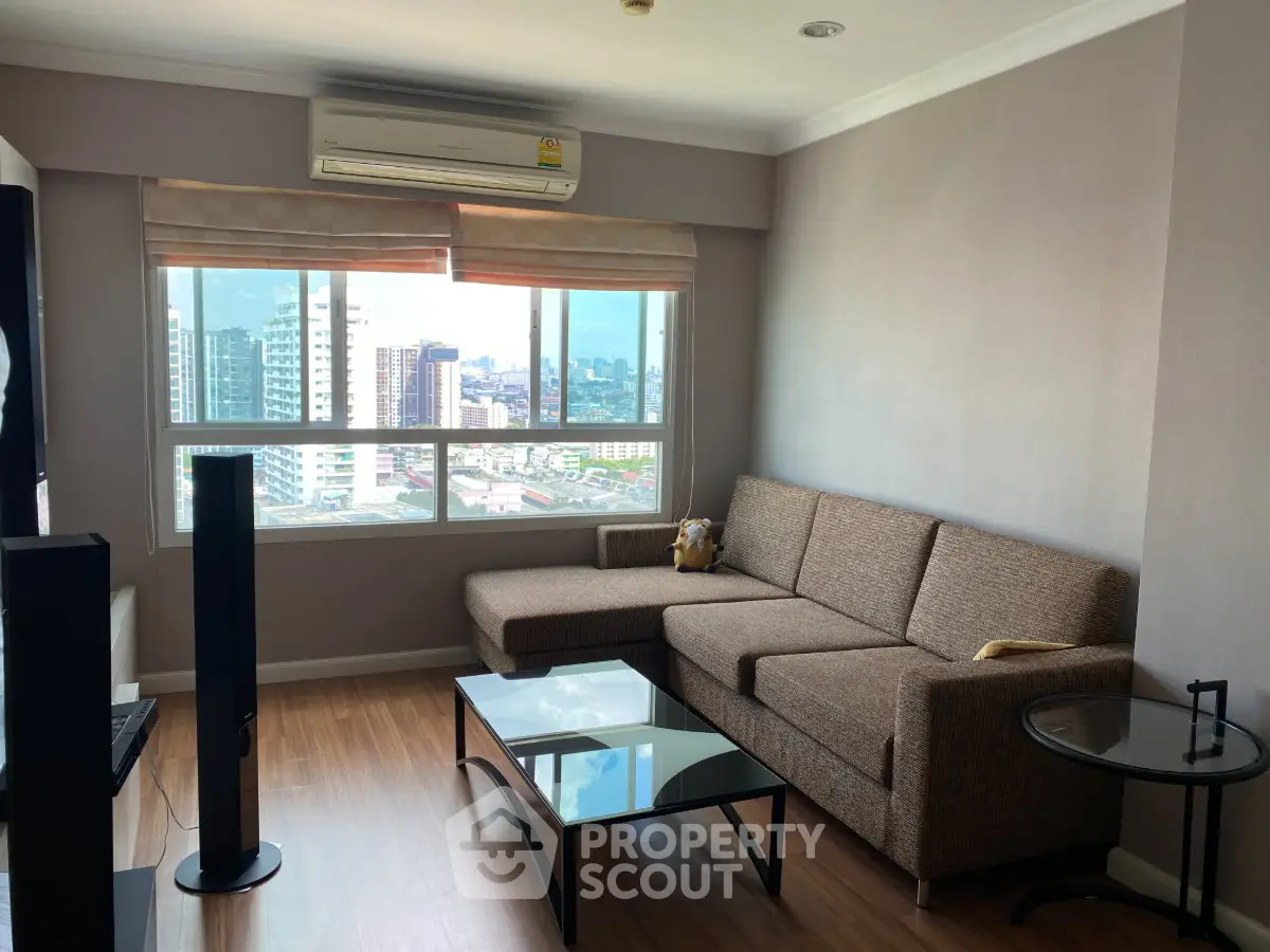Spacious living room with city view, featuring modern furniture and large windows for natural light.