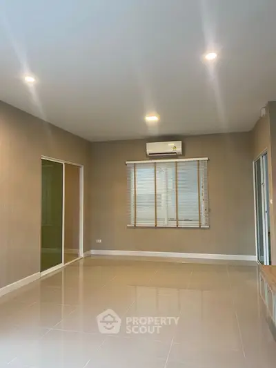 Spacious empty living room with modern tile flooring and large windows.