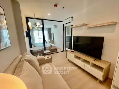 Modern living room with open layout and stylish decor, featuring a cozy sofa and large flat-screen TV.