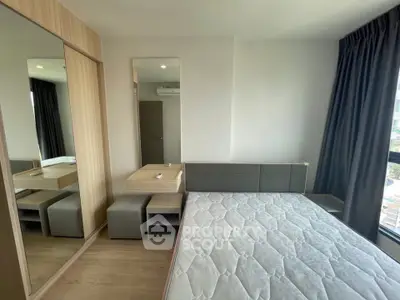 Modern bedroom with large window and mirrored wardrobe in a stylish apartment.