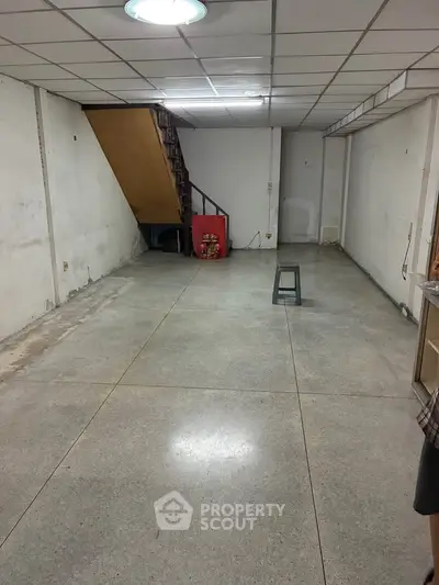 Spacious basement with concrete flooring and staircase, ideal for storage or renovation.